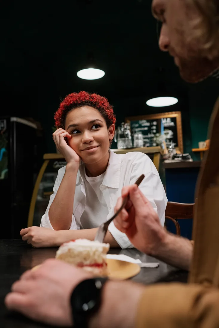 Vrouw luistert naar haar tafelgenoot tijdens een gesprek in een café
